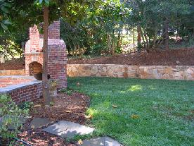 stone retaining wall opens up yard behind fireplace